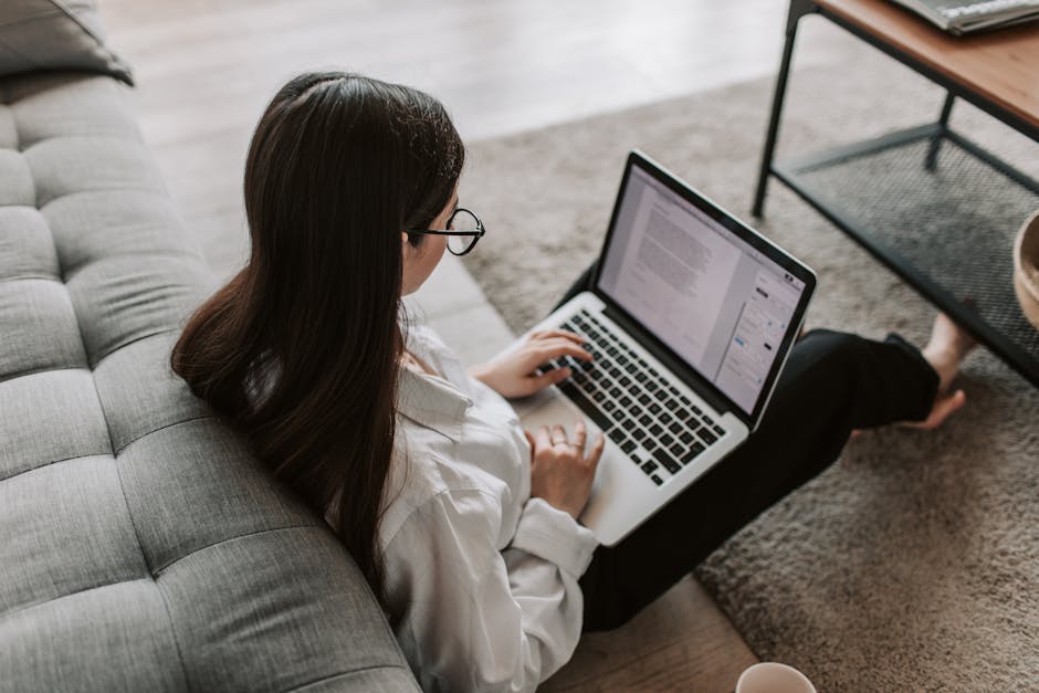 pexels-photo-4050290-4050290 Woman working remotely with a laptop on the floor next to a sofa, enjoying comfortable home office setup. Blog