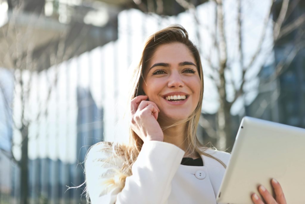 WebTazur Femme souriante en appel téléphonique tenant une tablette, illustrant un premier contact professionnel.